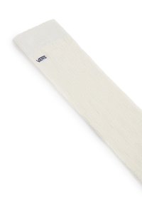 Chaussette crème avec un motif texturé, une bordure côtelée et un petit logo Vans bleu près du haut. Fabriquée en matériau tricoté doux.