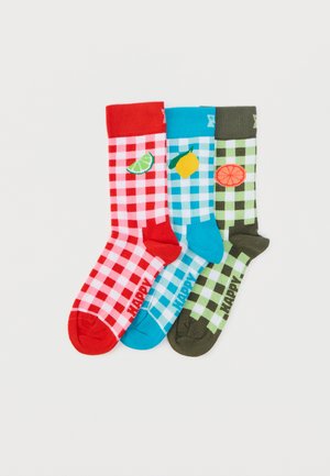 Trīs zeķu pāri ar sarkanā, zilā un zaļā gingemraksta rakstu, katrā ar augļu ikonām: laims, citrons un apelsīns. Dekoratīvi papildināts ar vārdu "PRIECĪGI."