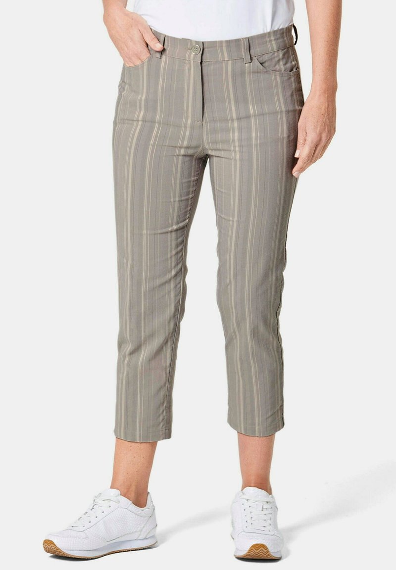 Helle graue, croppte Hose mit einem dezenten vertikalen Streifenmuster, ausgestattet mit vorderen Taschen und einem Knopfverschluss. Kombiniert mit weißen Sneakern.