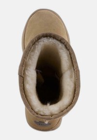 Botín de tobillo de ante en color marrón con un suave forro de borreguito, forma de punta redonda y un puño de tela texturizada. Etiqueta de marca notable en el costado.