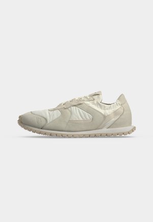 Hellbeiger Low-Top-Sneaker mit strukturierter Sohle, Obermaterial aus Velours und Stoff sowie Schnürverschluss, seitlich auf weißem Hintergrund dargestellt.