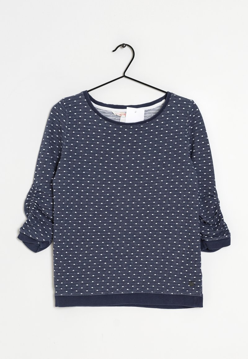 Camisa de manga larga azul marino con puntos blancos, textura acanalada, cuello redondo y mangas fruncidas. Etiqueta adjunta cerca del cuello.