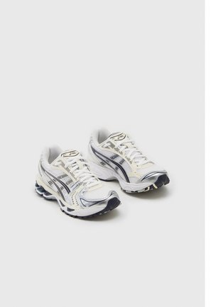Paire de chaussures de course Asics blanche et argentée avec des bandes noires du logo, tiges en mesh et semelles amortissantes sur un fond clair.