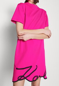 Rosa Baumwoll-T-Shirt-Kleid mit entspannter Passform. Es hat einen schwarzen bestickten "Zorlu"-Schriftzug am unteren Saum und kurze Ärmel.