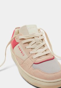 Różowe zamszowe i siateczkowe sneakersy z kremowymi akcentami, charakteryzujące się teksturowaną powierzchnią, okrągłym czubkiem i płaskimi sznurówkami. Logo wytłoczone na języku.