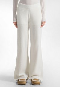 Witte, wijde broek gemaakt van zachte stof, met een geribde tailleband en naadloze zijkanten, die zachtjes taperen aan de onderkant.