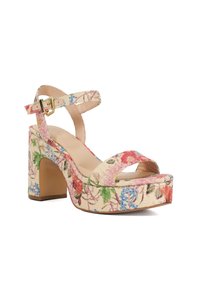 Sandale à talon haut imprimée floral avec des larges brides, arborant un design rose, vert et bleu sur un tissu beige. Talon carré.