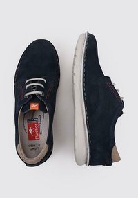 Zapatos de ante azul marino con acentos beige, suela gris, punta redonda y costuras rojas en contraste. Presentan cordones y etiqueta con logotipo en el interior.