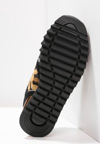 Sneaker con suola in gomma nera testurizzata e tomaia con stampa leopardata in tonalità di marrone e nero, caratterizzata da un design retrò.