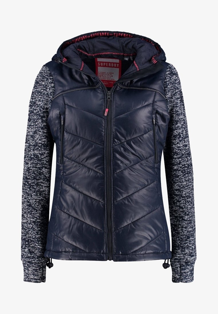 Marynarka w kolorze granatowym z pikowanym, błyszczącym przodem oraz teksturowanymi, wzorzystymi rękawami. Posiada kaptur, pełny zamek oraz regulowany dół ze sznurkami.