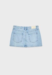 Mini-jupe en denim bleu clair avec deux poches arrière, passants de ceinture, et une petite étiquette beige sur la ceinture, vue de dos.