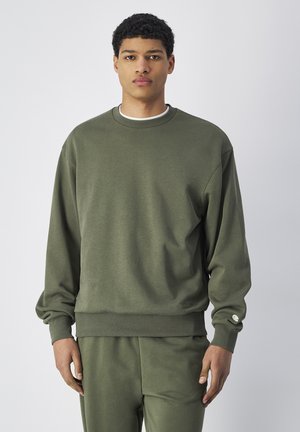 Groene sweatshirt van zacht materiaal, met een ronde hals, ribgebreide manchetten en een relaxte pasvorm. Inclusief een subtiele logo aan de zijkant.