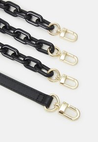 Quatre lanières noires pour sac à main avec des fermoirs en métal doré, trois en grosses mailles de chaîne en plastique et une en cuir texturé.