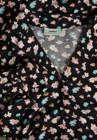 Czarna bluzka w kwiaty z intensywnym wzorem różowych, niebieskich i białych kwiatów, z dekoltem w kształcie litery V i zapięciem na guziki.