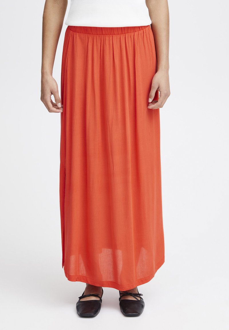 Maxikjol i ljus orange tyg med textur, med elastisk midja och sidoklyftor. Buren med svarta ballerinas.
