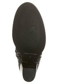 Semelle de chaussure noire texturée avec des rainures horizontales, marquée "FABRIQUÉ AU PORTUGAL" et taille "36". Présente un design à talon haut.
