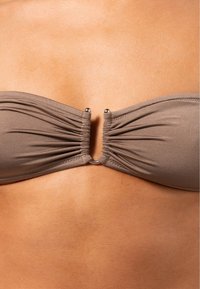 Brauner Bandeau-Bikini-Oberteil mit gerafftem Stoff und zentralem silbernen Verschlussdetail; glatte Textur und nahtlose Kanten.