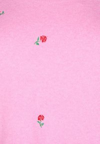 Rosa gestrickter Pullover mit kleiner roter Rosenstickerei und grünen Blättern, die ein Blumenmuster über den Stoff bilden. Weiche Textur.