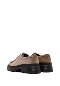Chaussures en suède marron à bout rond, avec un col rembourré et une semelle en caoutchouc noir épaisse présentant des motifs de traction.