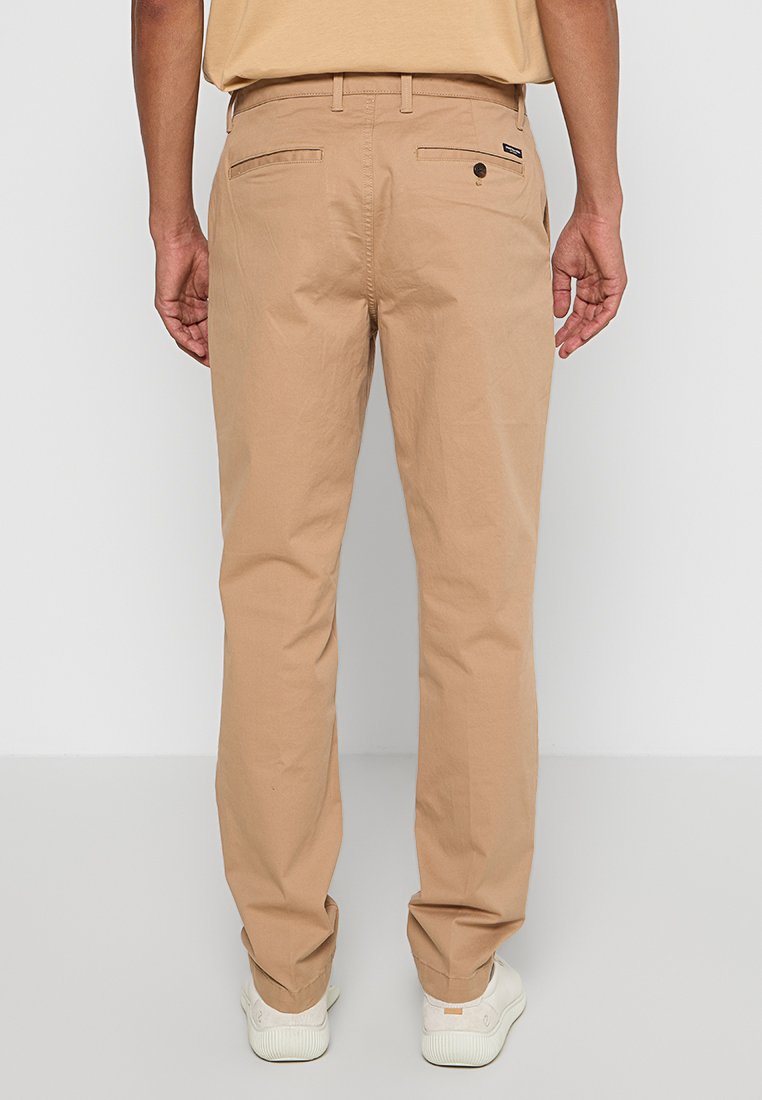 Beige Chinos mit geradem Bein, aus Baumwolle, ausgestattet mit zwei Gesäßtaschen und einem Logo-Label in der Nähe des Bundes.