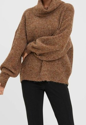 Pull marron à col roulé en tricot ample avec manches ballon, porté avec un pantalon noir ajusté sur une personne debout.