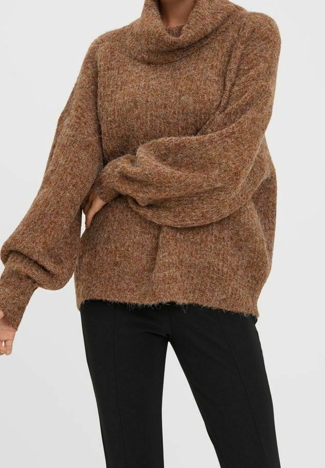 Pull marron à col roulé en tricot ample avec manches ballon, porté avec un pantalon noir ajusté sur une personne debout.