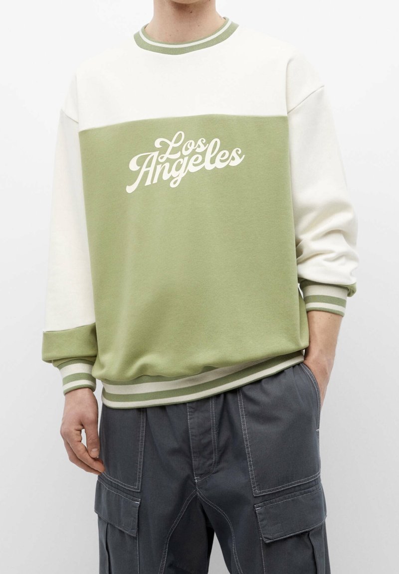 Olivengroene en crèmekleurige sweatshirt met "Los Angeles" in het wit bedrukt, voorzien van een geribde kraag en manchetten met gestreepte accenten.