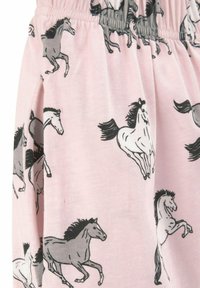 Svetloružová tkanina s opakujúcim sa vzorom hrdzavých sivých a bielych koní. Elastický pás na vrchu; mäkká bavlnená textúra.