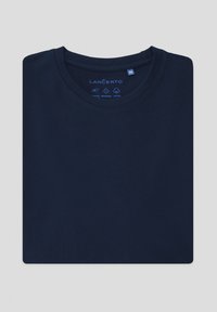 Granatowa bawełniana koszulka z okrągłym dekoltem, z instrukcją pielęgnacji w niebieskim tekście na kołnierzu. Gładka faktura, złożona płasko.