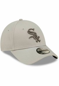 Beige baseball cap made of fabric, featuring an embroidered "Sox" logo in a darker tone, with a curved brim and adjustable band.