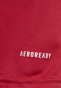 Tessuto atletico rosso con superficie testurizzata. Presenta il logo bianco "AEROREADY" in basso, che indica la tecnologia traspirante.