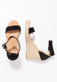 Sandali wedge in suede nero con tacco in juta intrecciato, dotati di cinture alla caviglia e soletta in pelle liscia. Design semplice con hardware minimo.