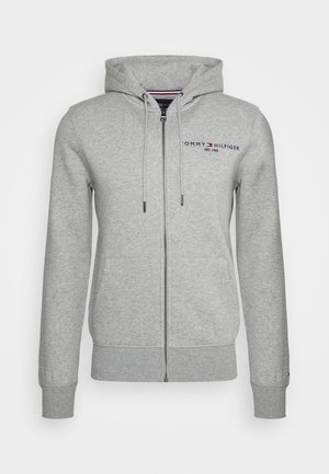 Sweat à capuche zippé gris clair avec poches avant, cordon de serrage à la capuche et petit logo Tommy Hilfiger sur le côté gauche de la poitrine.
