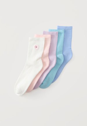 Cinq paires de chaussettes côtes en blanc, rose, violet, bleu clair et bleu, avec un petit patch rond près du bord-côte.