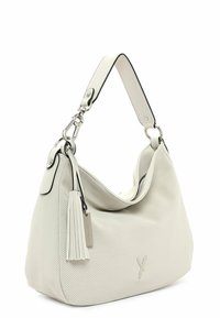 Sac à main blanc perforé avec une forme décontractée, bord noir contrastant, une bandoulière en cuir et un accent en pompon. Détail en métal argenté.