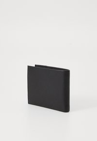 Portafoglio bifold in pelle nera in piedi su una superficie bianca con cuciture visibili sui bordi.