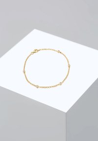 Gold chain bracelet featuring circular links and small, clear gemstones evenly spaced along the chain, finished with a lobster clasp.