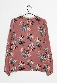 Langärmlige Bluse in Mauve mit floralem Muster in Schwarz, Blassrosa und Creme. Sie hat einen runden Ausschnitt und Gummibündchen.