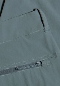 Lättviktig, mörk teal-tyg med en slät textur som har en dragkedja ficka och kontrasterande sömdetaljer.