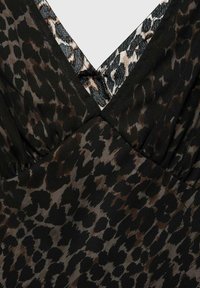 Tkanina s uzorkom leoparda ima V-izrez s crnim i smeškim tonovima. Materijal deluje glatko s blagim sjajem i detaljima nabora.