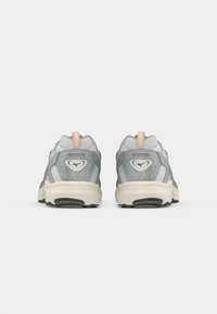Gray athletic shoes with a textured mesh upper, reinforced heel, and a cream rubber sole, featuring a tan pull tab and logo detail.