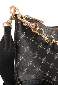 Sac à main en cuir noir avec une finition texturée, doté d'une chaîne en or et de quincaillerie, orné d'un motif de coquillages stylisés.