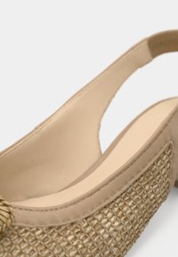 Μπεζ παπούτσι slingback με υφή πλεξίματος και λείες δερμάτινες λεπτομέρειες. Διαθέτει ανοιχτή πίσω πλευρά και στρογγυλεμένη μύτη.