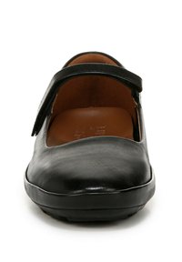 Chaussure en cuir noir avec un bout arrondi et une sangle unique sur le coup de pied. Texture lisse et design minimal, avec un intérieur marron.