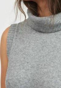 Ljusgrå ärmlös polokrage tröja i mjukt stickat tyg, med ribbade detaljer vid halsringningen och armhålorna.