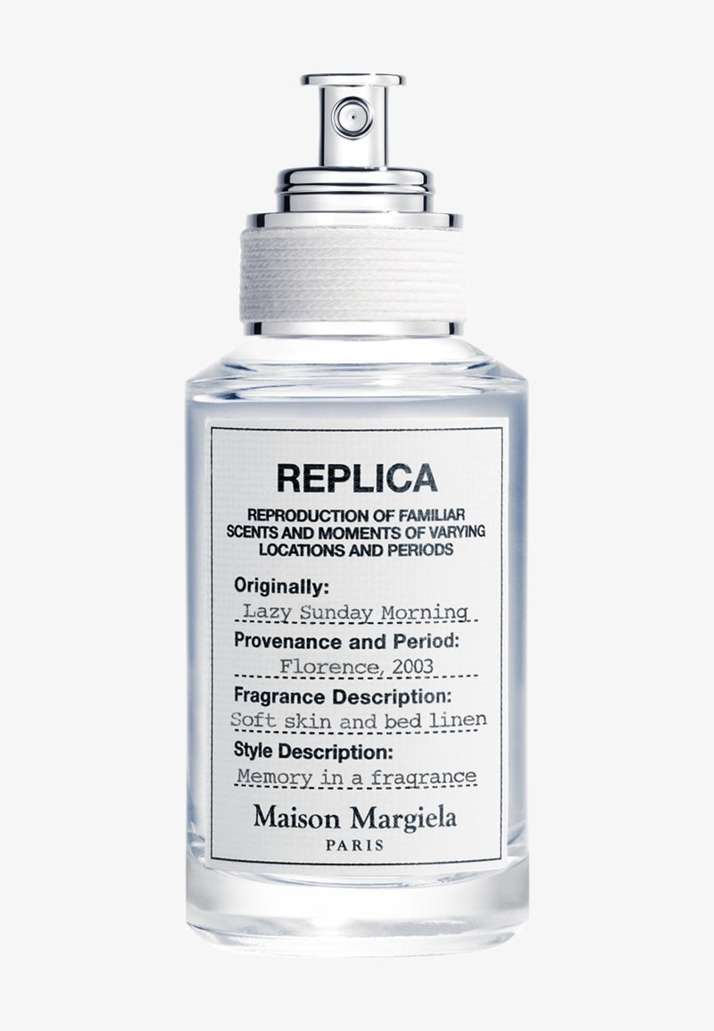 Gjennomsiktig glassparfymeflaske merket Replica av Maison Margiela med spraytopp og hvitt teksturert bånd nær dysen.