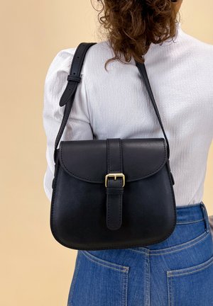 Borsa a spalla in pelle nera con pattina curva, fibbia in metallo dorato e tracolla regolabile. La borsa presenta una texture liscia e un design minimalista.