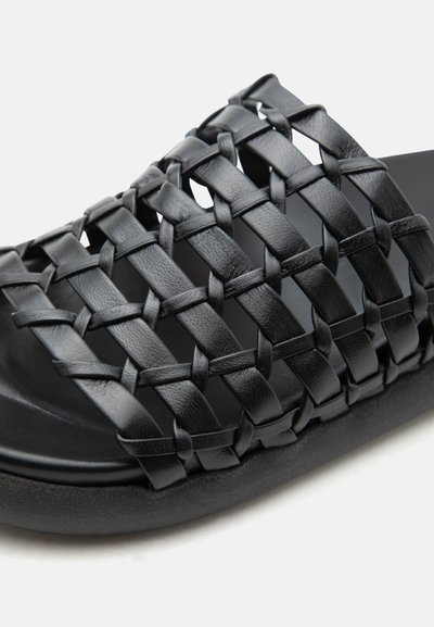 Μαύρο σανδάλι slide με φαρδιές πλεγμένες δερμάτινες λουρίδες που σχηματίζουν σχέδιο πλέγματος πάνω από το πάνω μέρος του ποδιού.