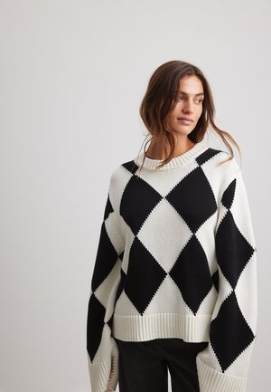 Pull en laine à motif argyle noir et blanc. Présente un col rond côtelé et des manches larges.