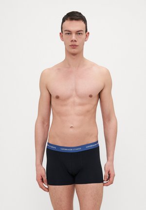 Schwarze Boxer-Briefs mit einem blauen Bund, beschriftet mit "COPENHAGEN STUDIOS." Glatter Stoff, enganliegende Passform und Beinausschnitte, die bis zur Mitte des Oberschenkels reichen.